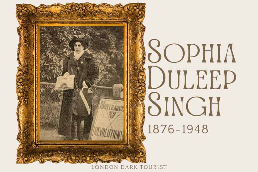 The image is a black and white photograph of Sophia Duleep Singh, an influential British suffragette of Indian heritage, who lived from 1876 to 1948. She is shown standing outdoors, wearing a large hat and a long coat, holding newspapers and a bag, next to a sign that reads "Votes for Women." The sign's presence and her determined expression suggest her active role in the suffragette movement. Her name and lifespan are prominently displayed in an elegant typeface, and the image is framed within a detailed, ornate golden picture frame.