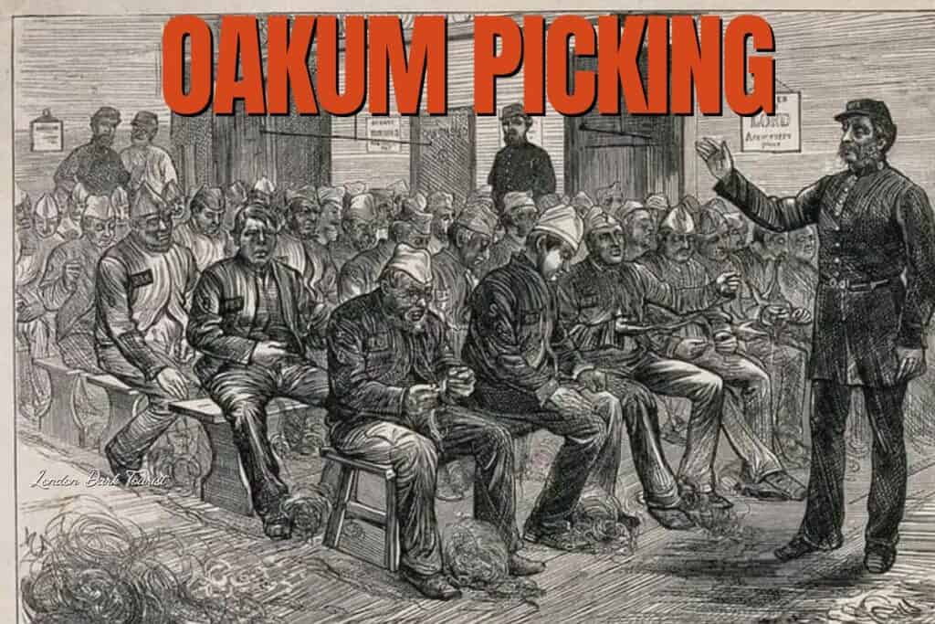 Detailed Victorian engraving titled 'OAKUM PICKING' depicts a group of men, seated in rows, painstakingly untwisting old ropes to salvage the fibers. An overseer stands to the right, gesturing as if addressing the workers. This image encapsulates the tedious and labor-intensive job of oakum picking, often undertaken by the poor and imprisoned as one of the worst jobs of the era.